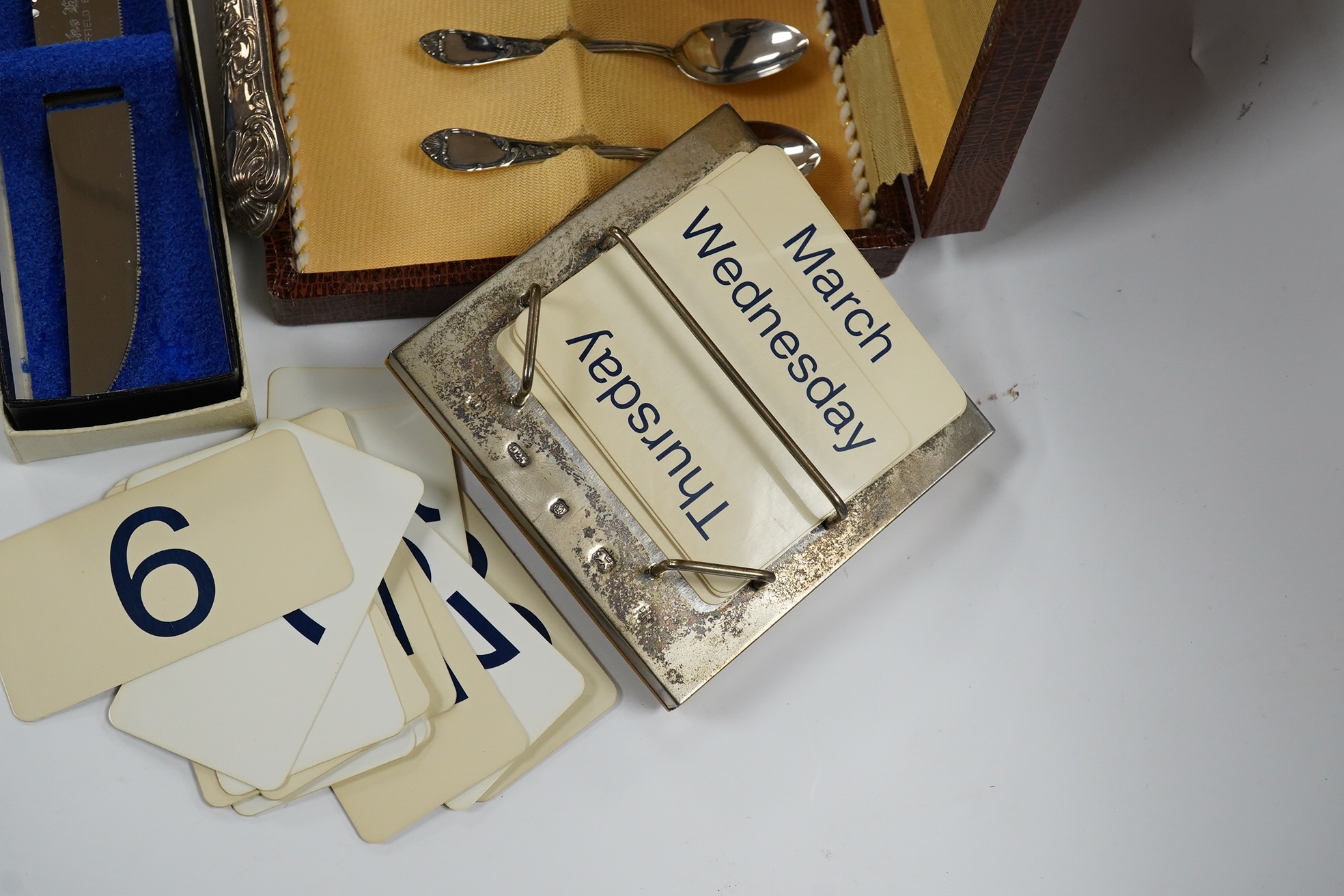 Sundry silver including a silver handled cake slice and similar bread knife, a cased set of six Italian 800 standard coffee spoons, a modern silver mounted desk calendar and an unusual 925 long olive spoon? with removabl